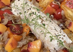 baked goat cheese in a dish with tomatoes, onions, and peaches