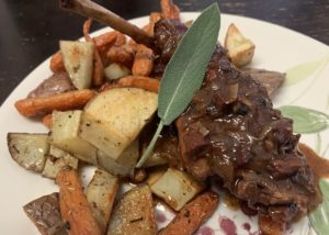 rabbit stew on a plate with roasted potatoes and carrots