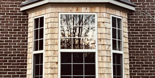 A bay window shingled with cedar shakes.